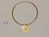 Gros plan sur un bracelet en or orné d'une pièce de monnaie