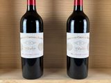 two bottles of red wine sit in a wooden box