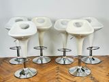 four white stools sitting on top of a wooden floor next to a white wall