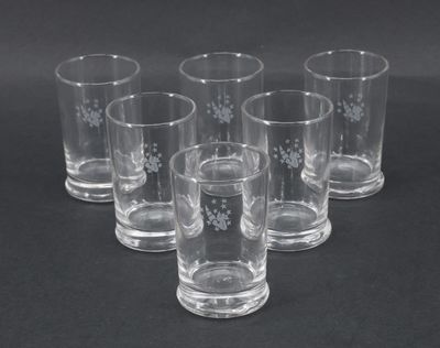 six verres à shot transparents ornés de flocons de neige, posés sur une surface noire