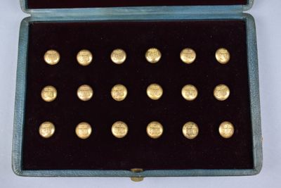a blue case with gold buttons in it on a white surface