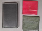 three different colored wallets sitting next to each other on a table