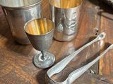 silver cups and spoons sitting on a wooden table
