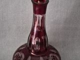 purple glass perfume bottle with floral design on it on a gray background