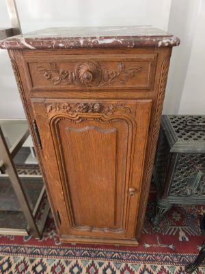 une vieille armoire en bois avec un plateau en marbre, posée sur un tapis