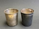 two silver cups sitting next to each other on a table