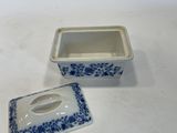 a small blue and white box with a lid on a white table