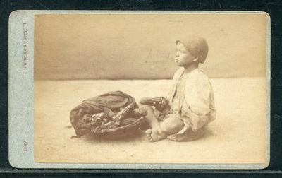 une vieille photo d'un jeune garçon assis par terre avec un gant de baseball
