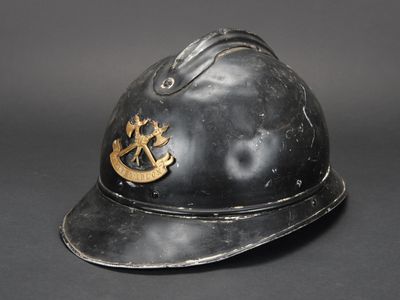 un vieux casque de pompier noir orné d'un insigne doré