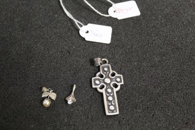 a silver cross and a pair of earrings on a table