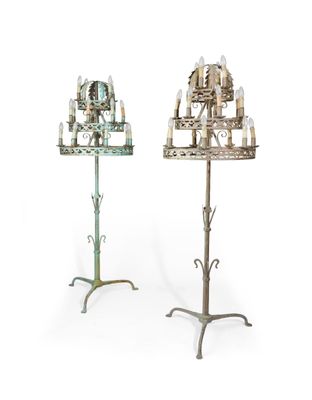 paire de chandeliers anciens en fer forgé avec des bougies posées sur des socles