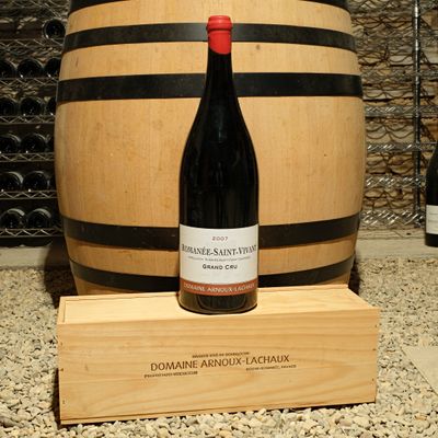a bottle of wine sitting next to a barrel of wine