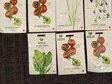 six packets of tomato seeds on a black couch