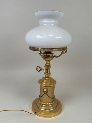 an antique brass table lamp with a white glass shade on it