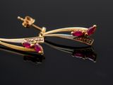 pair of gold and ruby earrings on a black surface