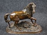 bronze statue of a horse running on a rock on a black background