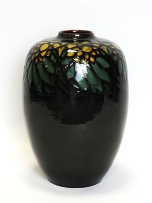 a black vase with yellow and green designs on it