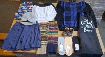 une table sur laquelle sont posés beaucoup de vêtements et de chaussures