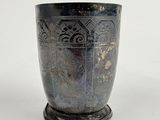 a silver cup that is sitting on a white surface