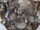 a silver tea set on a table with other silver items
