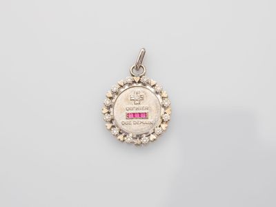 a small silver medal with a pink stone in the center