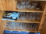 a wooden cabinet filled with wine glasses on top of it