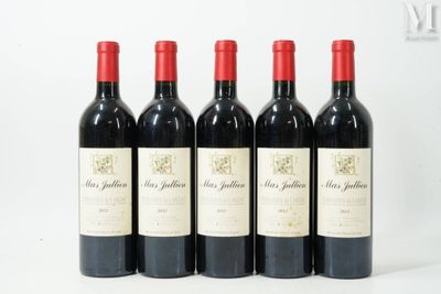 quatre bouteilles de vin rouge sont alignées sur une surface blanche