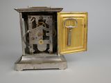 a silver clock with a key inside of it