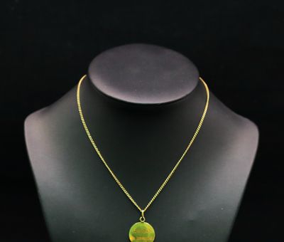 un collier avec un pendentif vert et jaune sur un mannequin