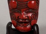 a small red sculpture of a face on a stand