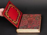 an open book with a red cover sitting on top of a black table