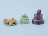 trois petites figurines de bouddhas assis les uns à côté des autres