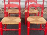 pair of red chairs with wicker seats in front of a white wall