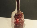 un vase rouge et blanc posé sur une table blanche