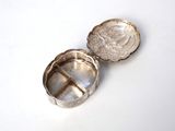 a small silver box with a coin inside of it