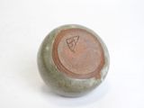 a small green vase with a brown lid on a white surface