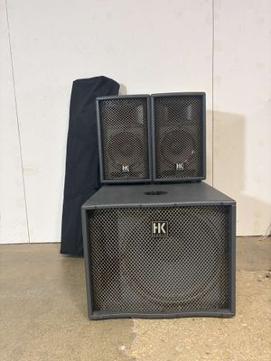 two black speakers sitting on top of each other in front of a white wall