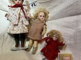 three dolls sitting next to each other on a white cloth