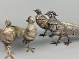 three silver metal birds are standing next to each other