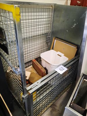 a large metal cage with a bin of food inside of it