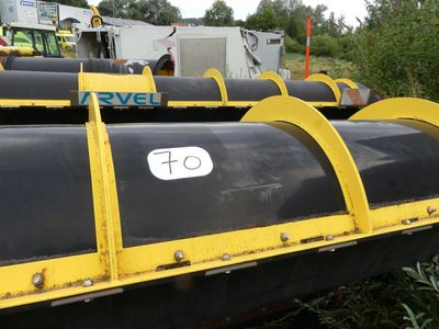 yellow and black pipes are lined up in a field with a truck in the background