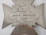 une croix en métal portant une inscription, posée sur une table