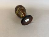 a small vase with a brown base on a table