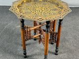 une table-plateau ancienne en laiton, avec des pieds en bois et un plateau en métal posé dessus