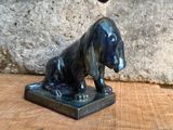 une statue représentant un chien assis sur une table en bois