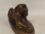 bronze statue of a dog resting on a piece of wood