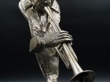 statue en bronze représentant un homme jouant de la trompette sur fond noir