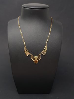 a gold necklace on a mannequin with a black background