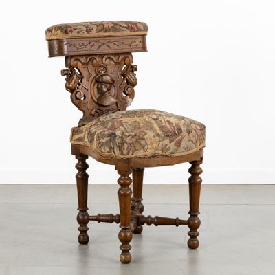 une chaise ancienne avec une assise rembourrée à motifs floraux et des pieds en bois