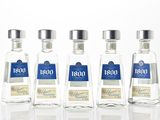 four bottles of liquor are lined up on a white surface